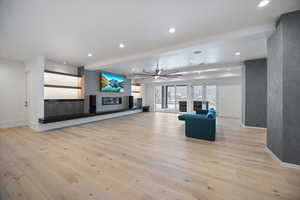 Unfurnished living room featuring recessed lighting, light wood-type flooring, ceiling fan, and a glass covered fireplace