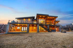 Back of house at dusk with a patio and a deck