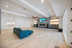 Unfurnished living room with beamed ceiling, light wood-style flooring, a glass covered fireplace, recessed lighting, and french doors