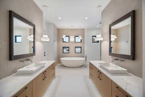 Full bath with tile walls, decorative backsplash, two vanities, a soaking tub, and recessed lighting