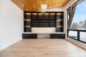 Unfurnished dining area featuring built in desk, light wood-style floors, hanging lights, wood ceiling, and built in shelves