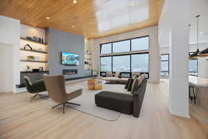 Living area featuring a high wood ceiling, light wood-type flooring, a large fireplace, and recessed lighting