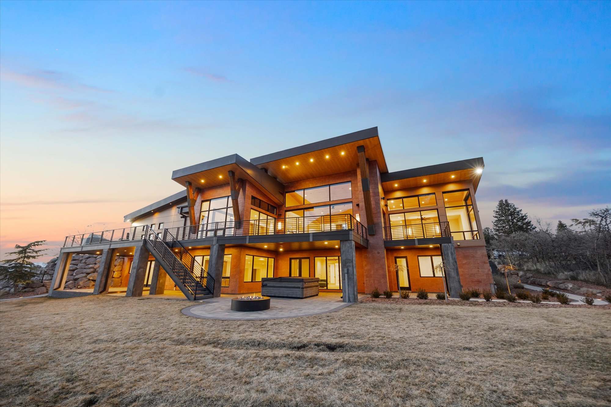 Back of property at dusk featuring a patio area, a jacuzzi, a fire pit, and a deck