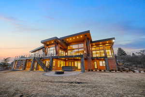 Back of property at dusk featuring a patio area, a jacuzzi, a fire pit, and a deck