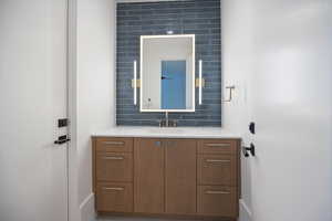 Bathroom featuring vanity and decorative backsplash