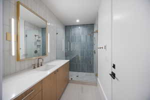 Full bathroom featuring vanity, a stall shower, recessed lighting, and tile walls
