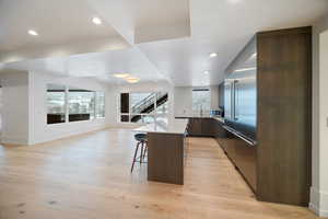 Kitchen featuring modern cabinets, a kitchen bar, light wood finished floors, plenty of natural light, and recessed lighting