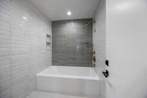 Bathroom featuring  shower combination, recessed lighting, and tile walls