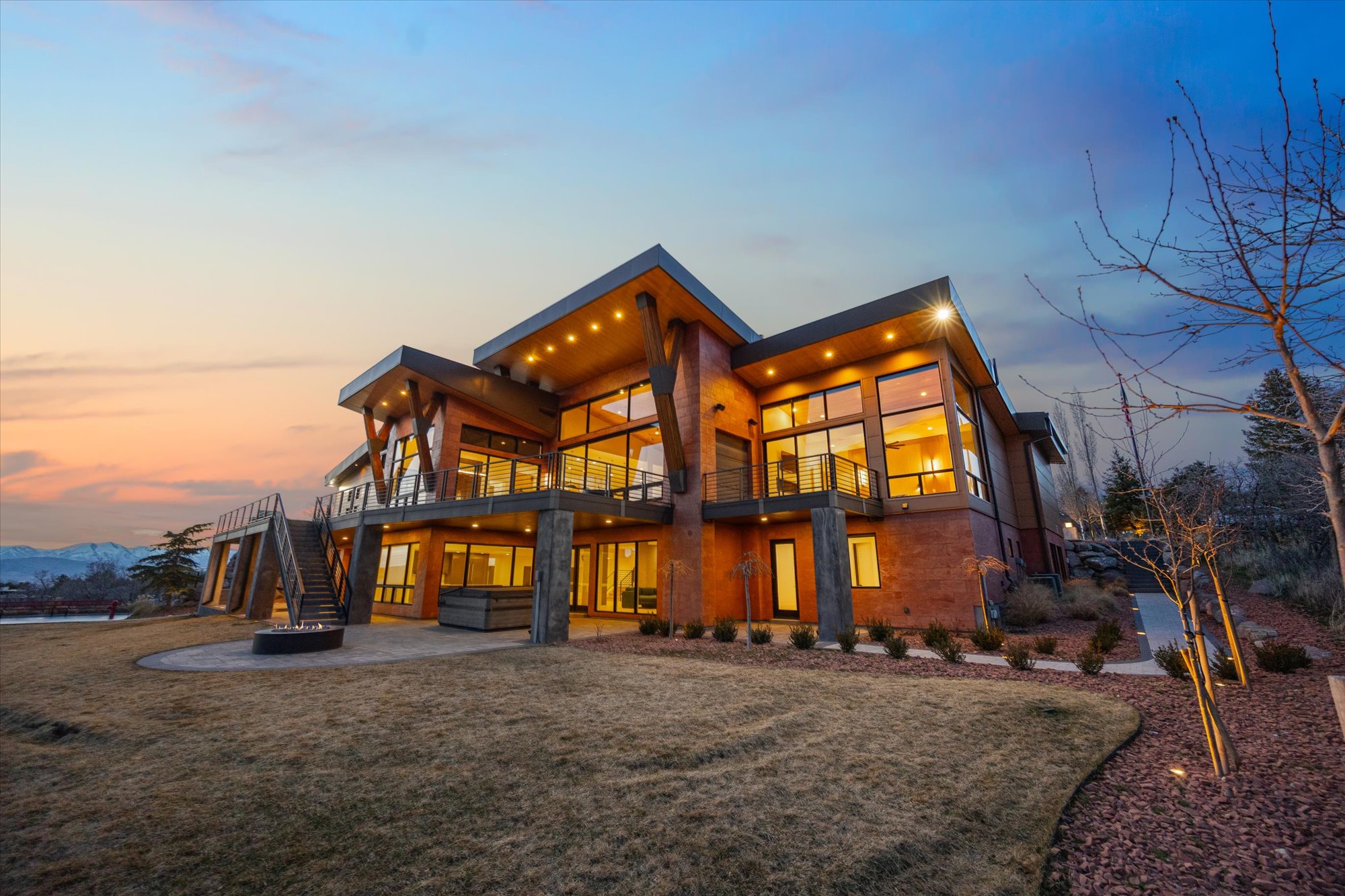 Rear view of property featuring a patio, a balcony, a lawn, a mountain view, and a fire pit