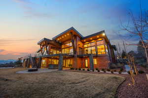Rear view of property featuring a patio, a balcony, a lawn, a mountain view, and a fire pit