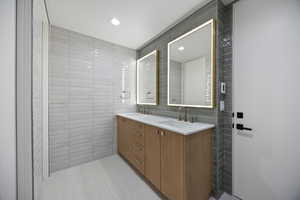 Bathroom featuring tile walls, double vanity, and recessed lighting