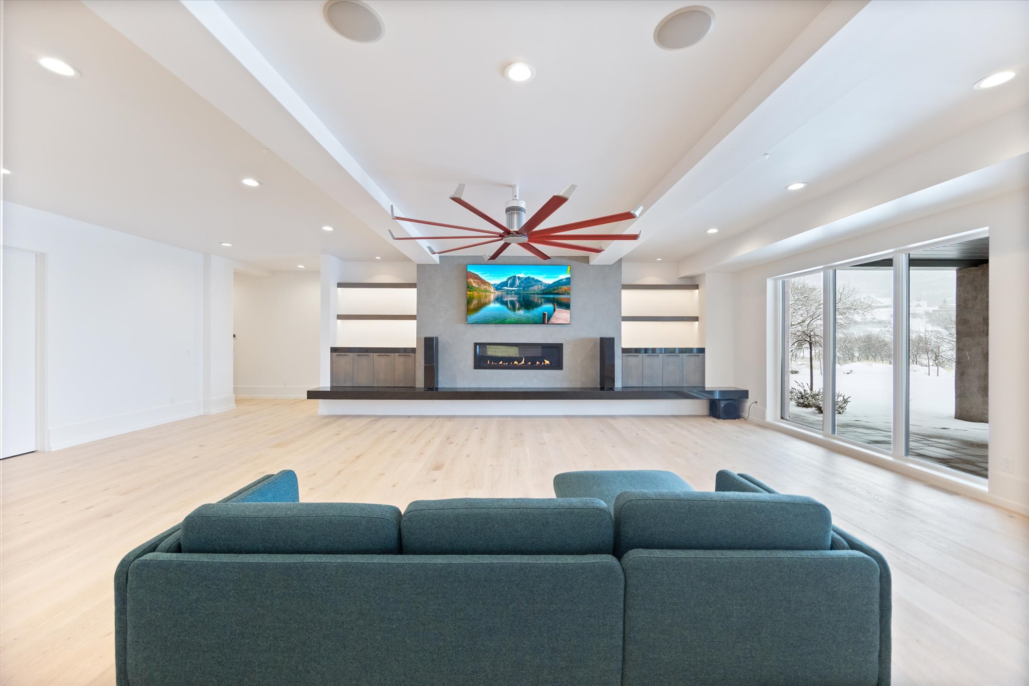 Living area with light wood-style floors, a ceiling fan, a warm lit fireplace, and recessed lighting
