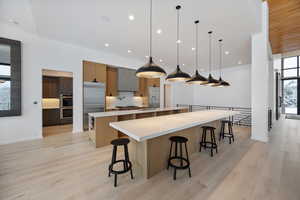 Kitchen featuring light wood finished floors, a kitchen breakfast bar, stainless steel appliances, and two tone cabinets