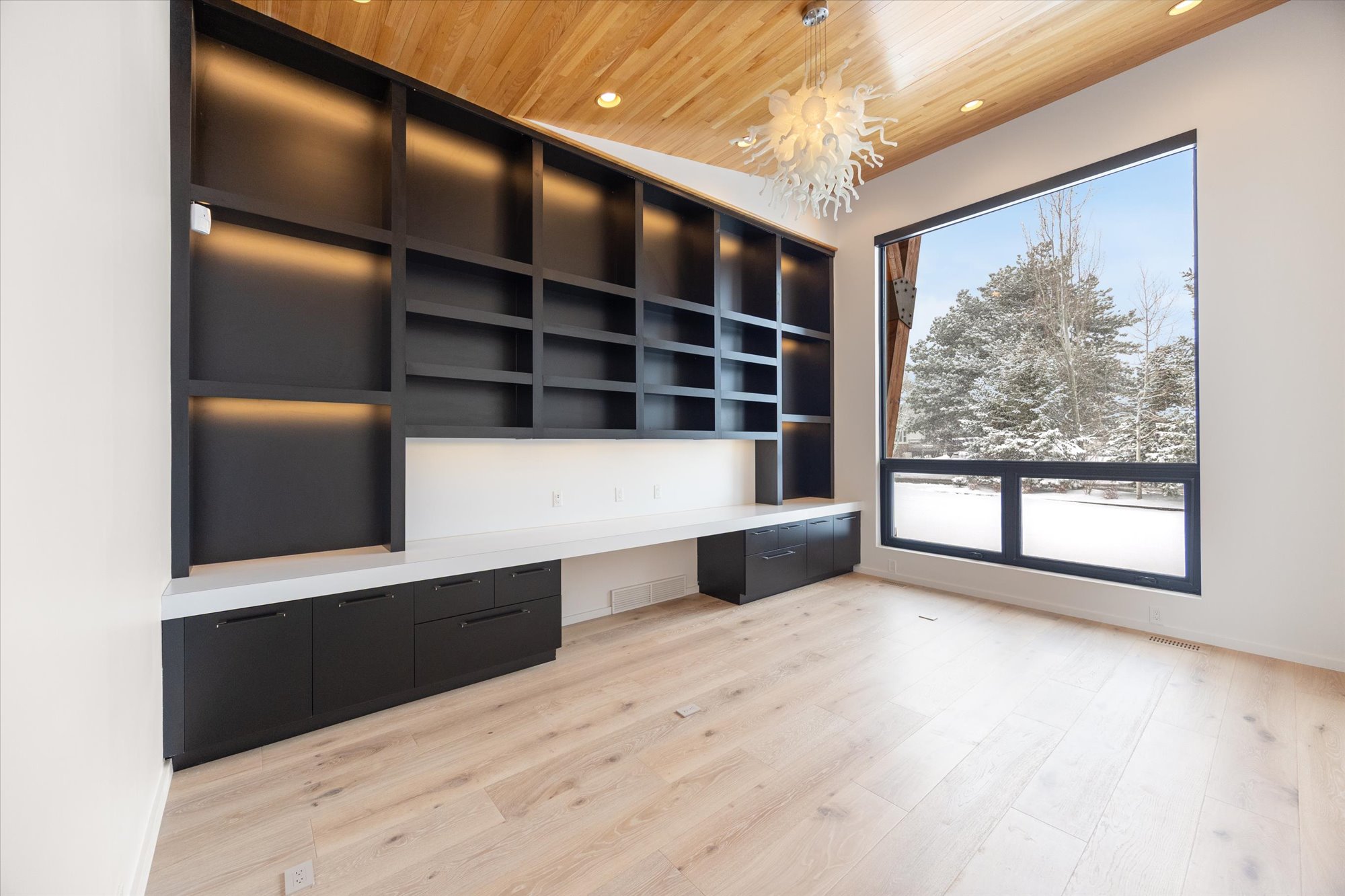 Unfurnished office featuring built in desk, light wood-style floors, hanging lights, and wooden ceiling