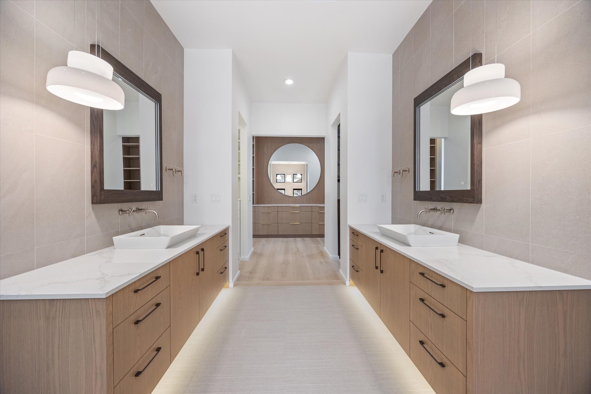 Full bath with tile walls, two vanities, and recessed lighting