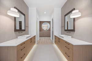 Full bath with tile walls, two vanities, and recessed lighting