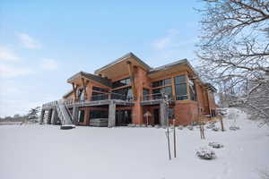 Snow covered house featuring stairway and a patio