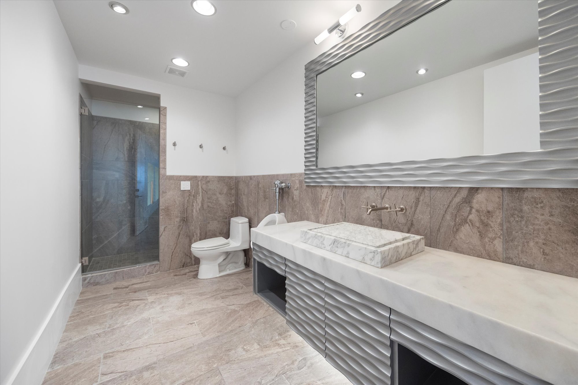 Bathroom with vanity, a marble finish shower, recessed lighting, light marble finish flooring, and tile walls