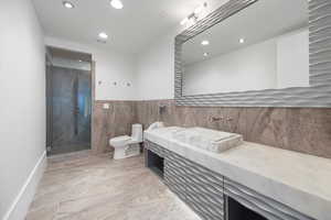 Bathroom with vanity, a marble finish shower, recessed lighting, light marble finish flooring, and tile walls