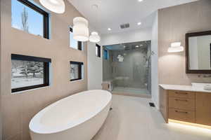 Full bath with tile walls, a soaking tub, a shower stall, vanity, and recessed lighting