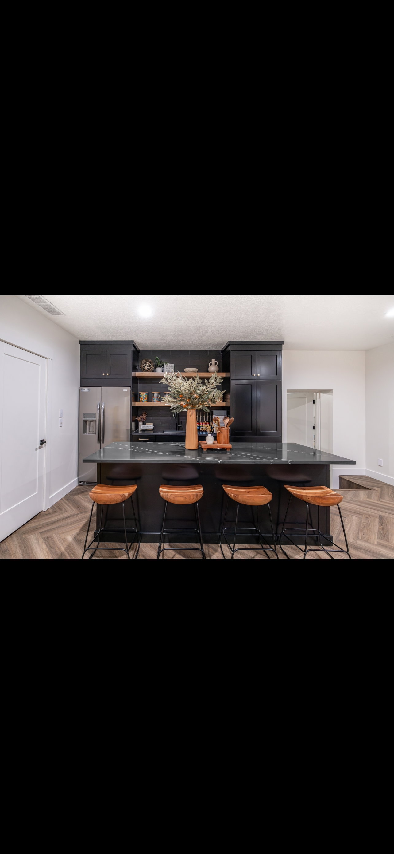 Bar featuring parquet flooring, stainless steel fridge with ice dispenser, gray cabinets, dark countertops, and recessed lighting