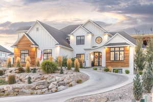 View of front of property featuring board and batten siding, roof with shingles, and curved driveway