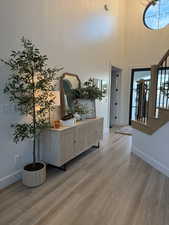 Foyer entrance with light wood-type flooring and a high ceiling