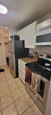 Kitchen featuring stainless steel appliances, light tile patterned floors, and white cabinets
