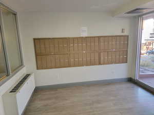 Unfurnished dining area featuring radiator, light wood-style floors, and mail area