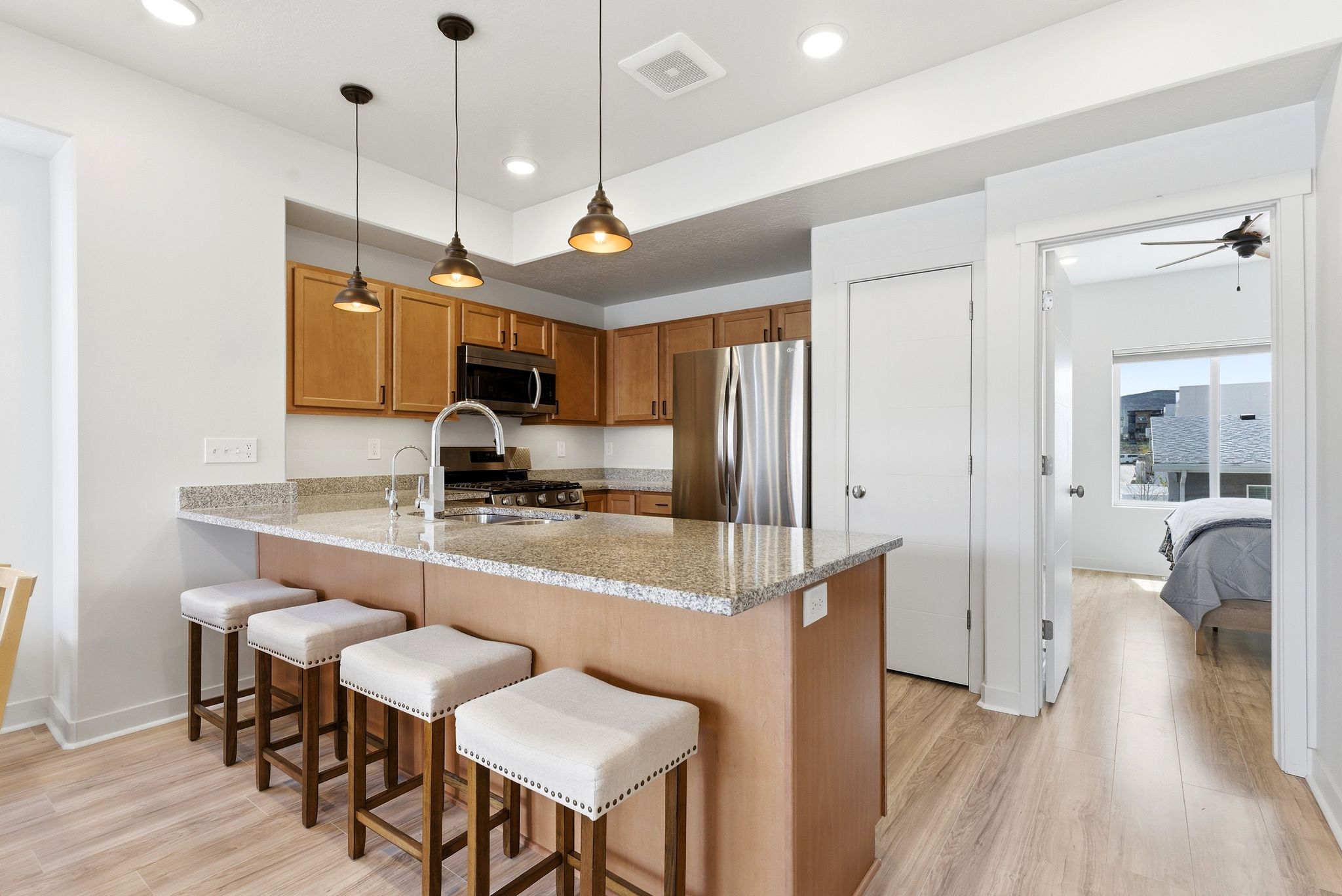 Kitchen with a peninsula, a kitchen bar, light wood finished floors, and light stone countertops