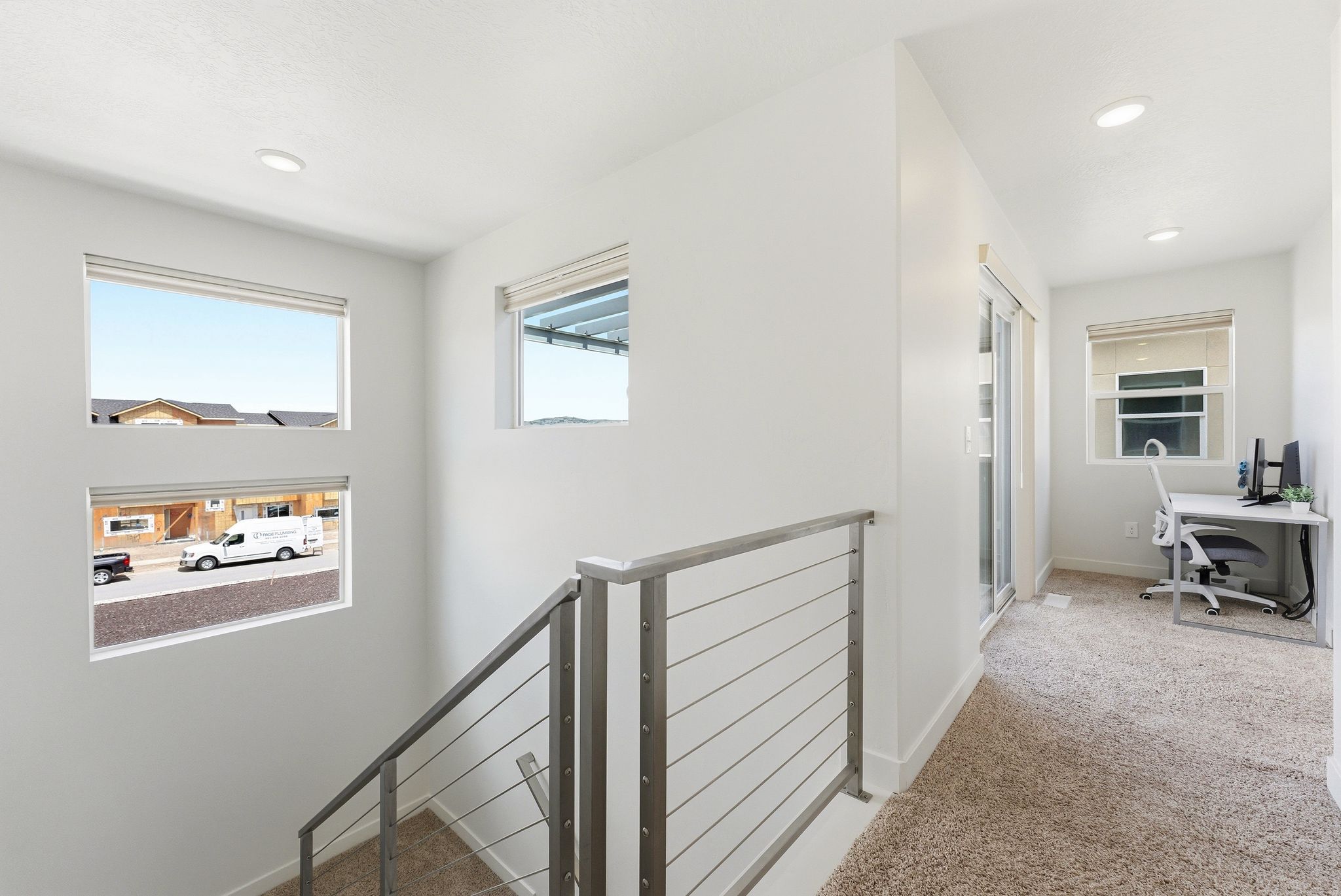 Corridor with an upstairs landing, an office area, light colored carpet, and recessed lighting