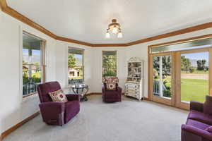Living area with carpet, french doors, a chandelier, crown molding, and a mountain view