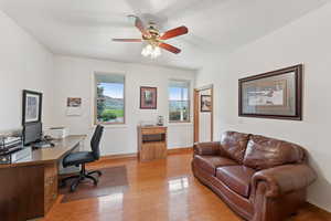 Home office with light wood-style flooring, ceiling fan, and a textured ceiling