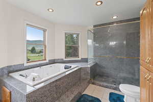 Bathroom with a shower stall, light tile patterned floors, a tub with jets, a mountain view, and recessed lighting
