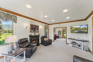 Living room with a glass covered fireplace, light carpet, ornamental molding, and a mountain view