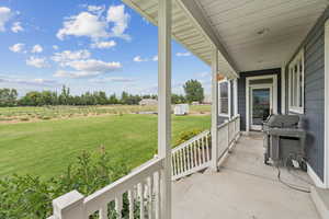 Covered porch featuring area for grilling, a yard, and a view of rural / pastoral area