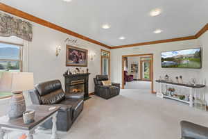 Living room featuring light carpet, a glass covered fireplace, plenty of natural light, and crown molding