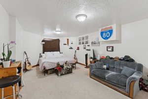 Bedroom with a textured ceiling and light carpet