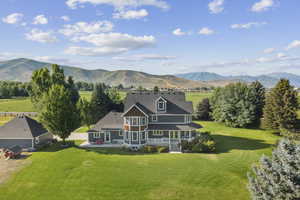 Rear view of house with a mountain view, a lawn, and a porch