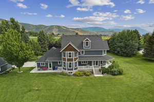Back of property with a lawn, a mountain view, a sunroom, and a patio area