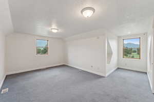 Bonus room with light colored carpet, healthy amount of natural light, and a mountain view