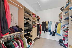 Walk in closet with attic access and light colored carpet