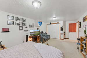 Bedroom with a textured ceiling, light carpet, and a closet