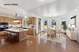 Kitchen with stainless steel appliances, light countertops, a textured ceiling, a kitchen island, and hanging lights