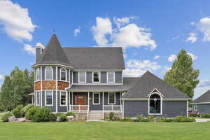 Victorian-style house with covered porch, a front lawn, roof with shingles, and a chimney