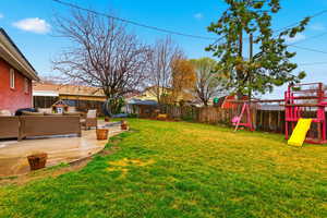 Fenced backyard featuring outdoor furniture, a playground, and a patio