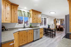 Kitchen with stainless steel appliances, light wood-style floors, light wood finish cabinetry, and light countertops