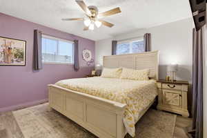 Bedroom featuring wood finished floors, multiple windows, a ceiling fan, and a textured ceiling