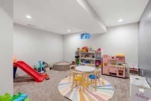 Recreation room with light colored carpet and recessed lighting