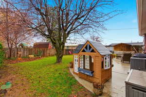 Fenced backyard with an outdoor structure and a patio area